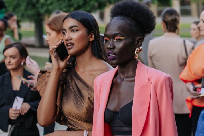 Two people dressed up with one talking on a phone.